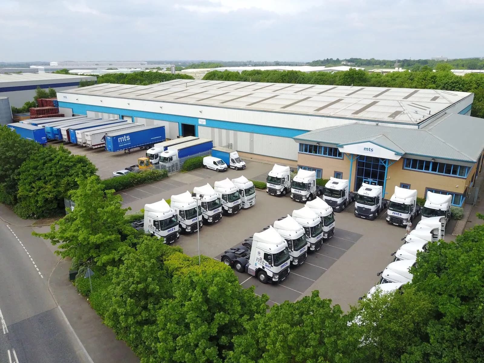 Aerial view of a haulage depot with rows of tractor units parked in front of the warehouse