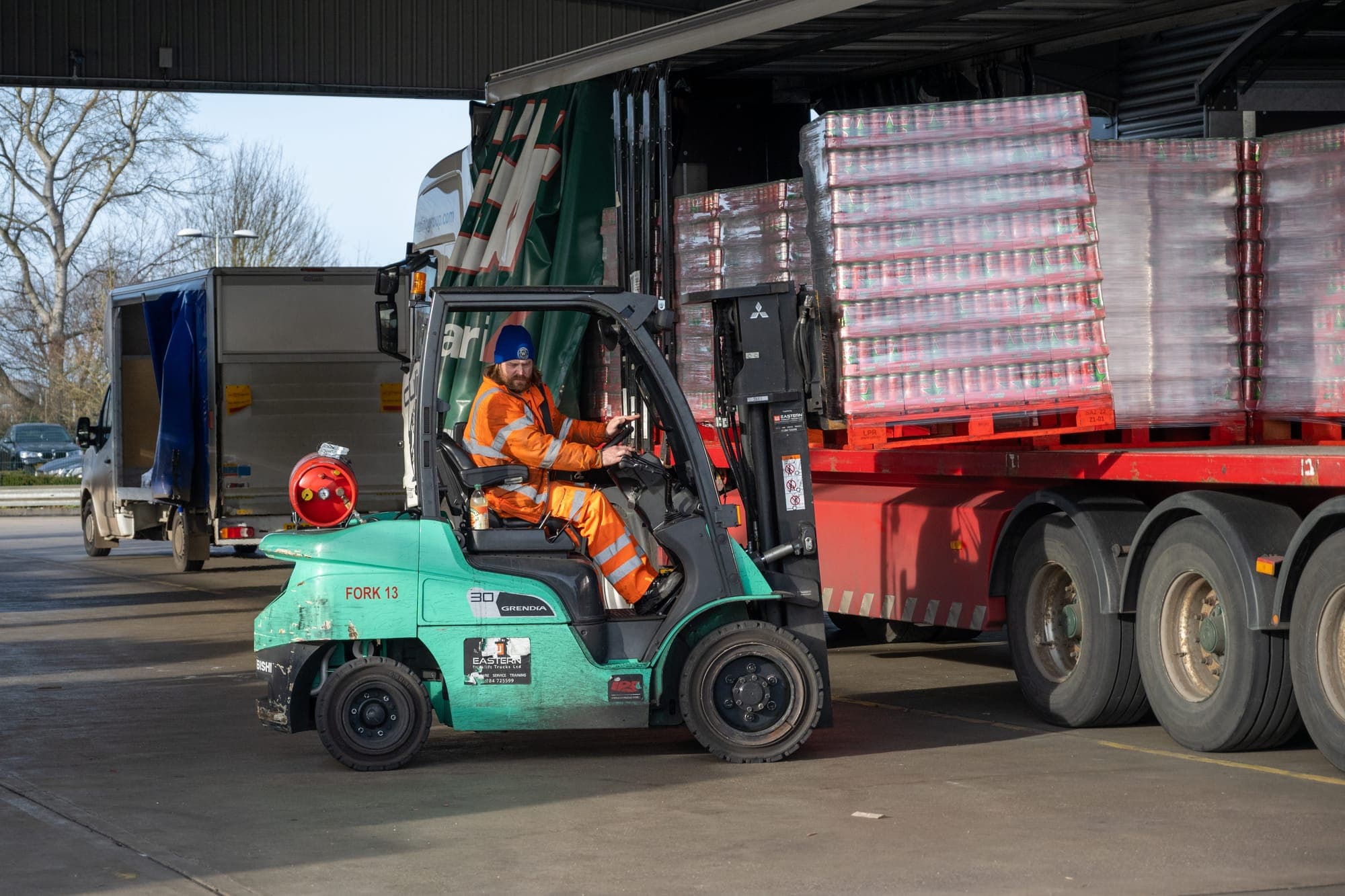 A mixed UK fleet in a depot yard, diesel HGVs alongside electric